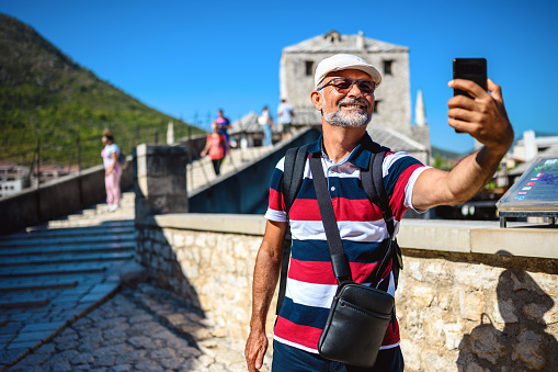 Turista masculino maduro tomando un selfie en el Puente Viejo, Mostar, Bosnia y Herzegovina. photo