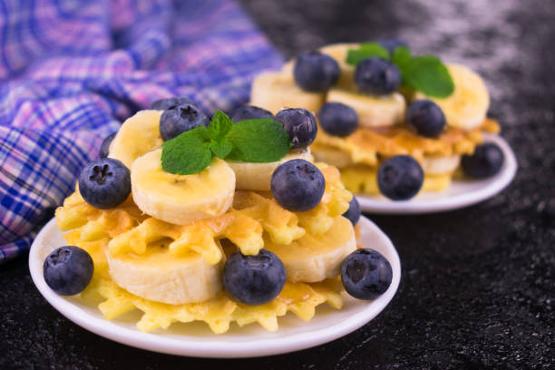 Waffles with banana and blueberries topped with maple syrup. Close-up.