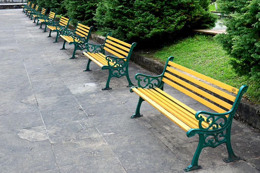 Bench chairs seating in Public park in a row at Ravangla Buddha Park in South Sikkim, India. Metal deck chairs stand in a row on the floor in a park. Colorful metal bench in a row for relaxing.