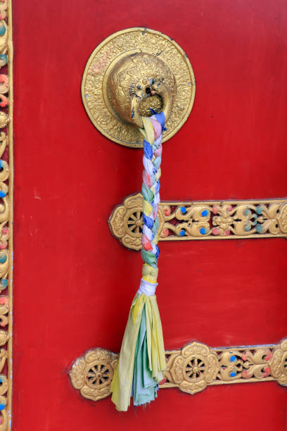 Ornate door handles and prayer scarves on ancient Buddha park monastery at Ravangla in South Sikkim, India. Red color door at Buddha Park of Ravangla. Door handles at Buddha Park Monastery in South Sikkim. manijas de puertas ornamentadas y bufandas de oración en el antiguo monasterio del parque buddha en ravangla en sikkim del sur, india. puerta de color rojo en buddha park de ravangla. manijas de las puertas en el monasterio de buddha park en sikkim.