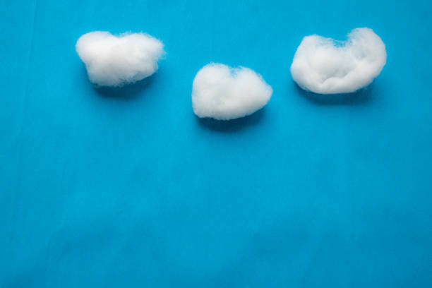 Clouds on blue sky reproduction using white cotton wool on blue creped paper background. Clouds on blue sky reproduction using white cotton wool on blue creped paper background. cotton cloud stock pictures, royalty-free photos & images