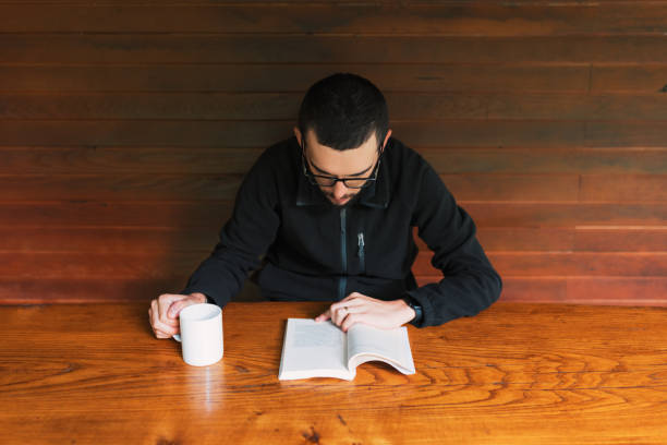 Young men reading book and drinking  cup of coffee