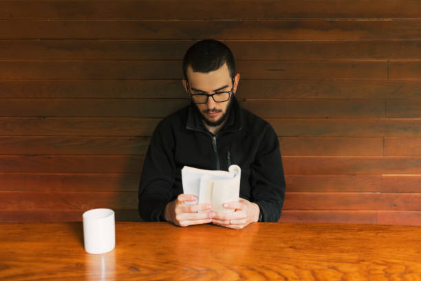 istock Young men reading book and drinking  cup of coffee 1272299852