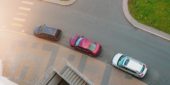 several cars parking along sidewalk on city street top view from above in summer day