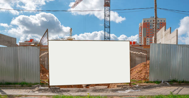 istock blank white information board on iron fence of construction site with crane 1272304520