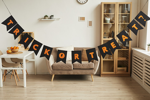 Horizontal no people shot of modern room interior with Trick or Treat lettering garland in it prepared for Halloween party