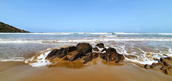 Waves approaching the shore and hitting the rocks situated on the beach at Gokarana