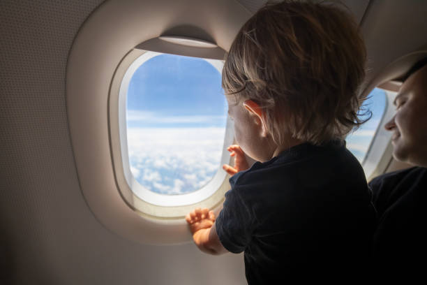 istock cute toddler points his finger at the sky through the window. first flight concept, traveling with children. 1272312846