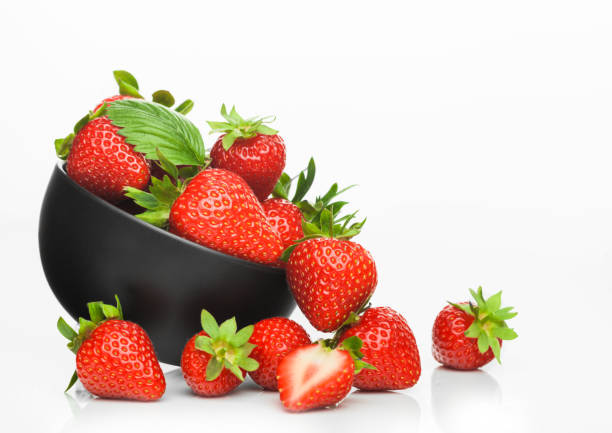 Fresh raw organic strawberries in black ceramic bowl plate on white background with berries next to it. Fresh raw organic strawberries in black ceramic bowl plate on white background with berries next to it. Space for text strawberry photos stock pictures, royalty-free photos & images