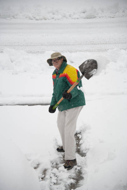 istock Senior Man in Green Jacket Shovels Snow 1272316972