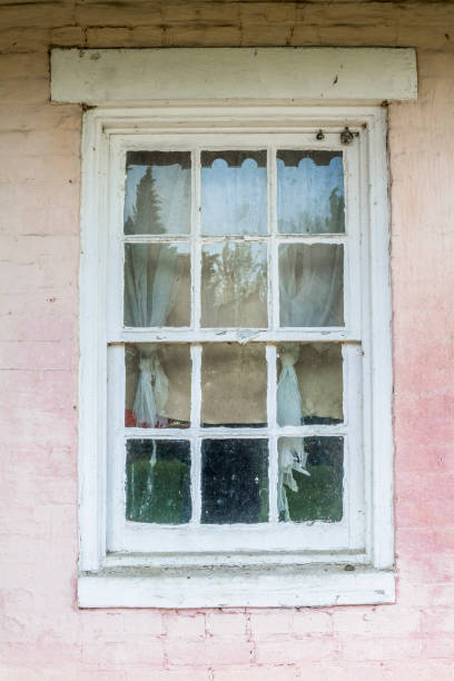 istock Old Window On Pink Wall With Tattered Curtains 1272320298