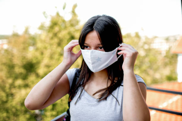 istock Caucasian girl putting on face personal protective face mask. 1272321513
