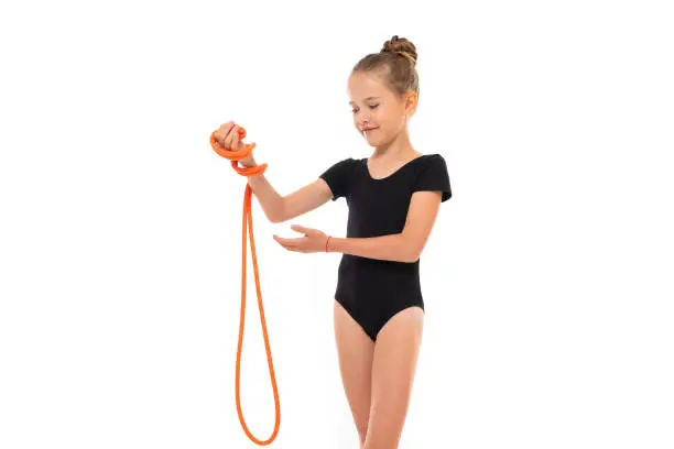 Picture of girl gymnast in black trico in full height keep a jumping-rope in her hand.