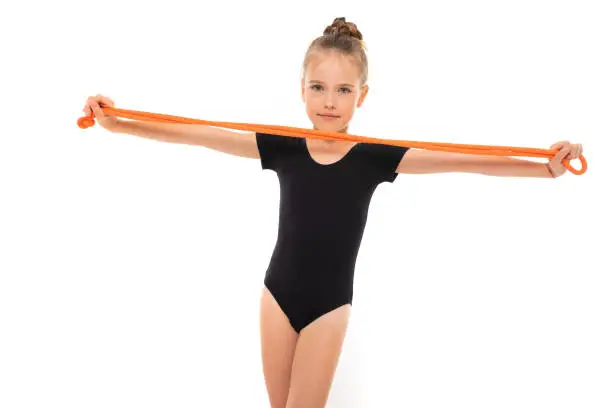Picture of girl gymnast in black trico in full height keep a jumping-rope in her hands.