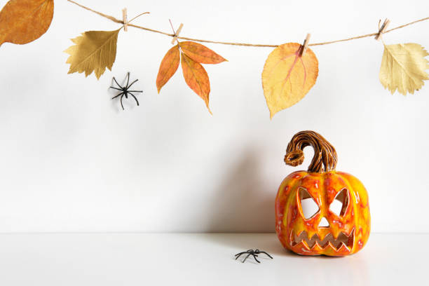 istock Halloween composition with ceramic pumpkin jack lantern and floral garland on table wall background. Home decoration 1272327161