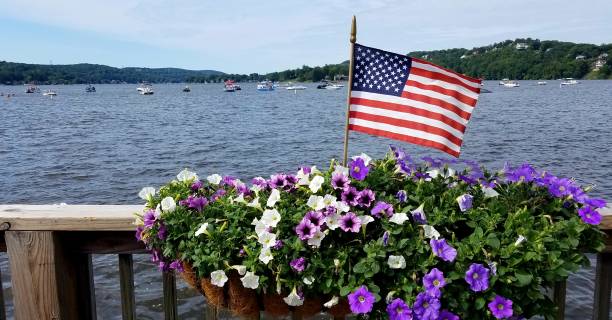 American Flag and Very Large Hanging Floral Basket Against Blue Waters in Background stock photo