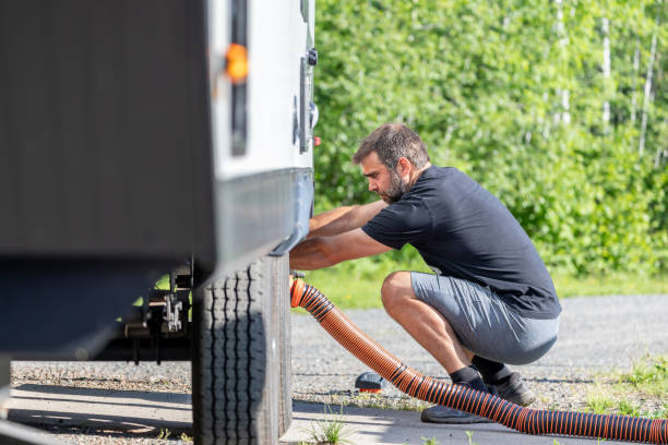istock Man Emptying RV Sewer at Dump Station After Camping 1272334338