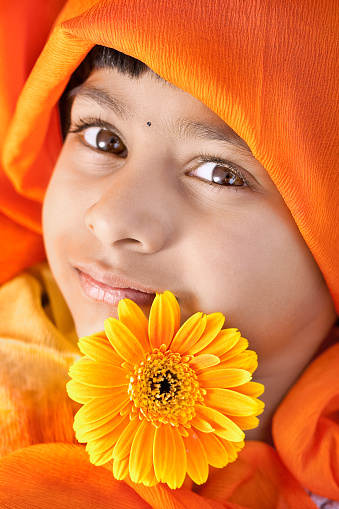 Portrait of cute Indian kid with daisy flower.
