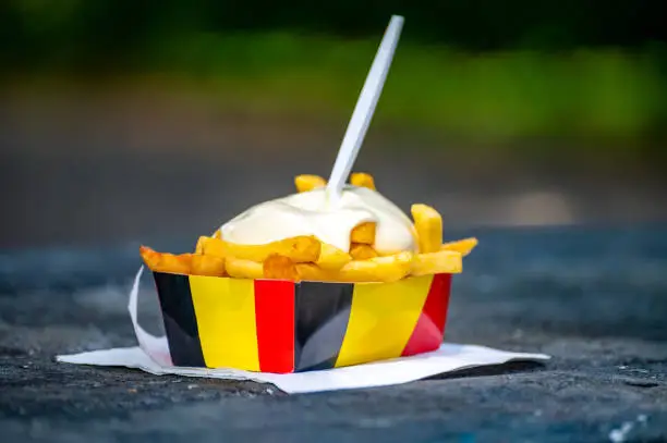 Belgian street and fast food, paper box in colors of Belgian flag with fried potato frit chips and mayonnaise sauÑe.