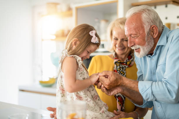 personnes âgées heureuses jouant avec leur petite-fille dans la cuisine. - grandparent grandfather grandmother child photos et images de collection