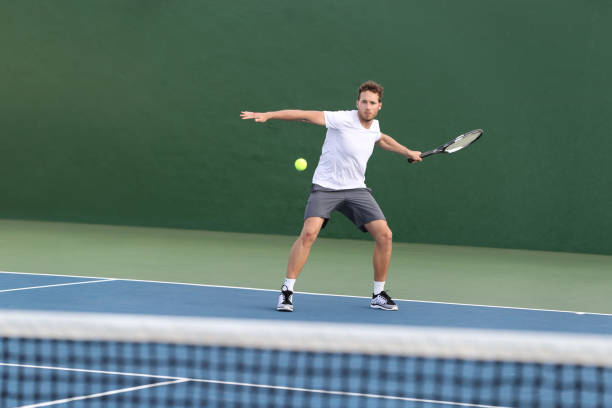 professional tennis player athlete man focused on hitting ball over net on hard court playing tennis match with someone. sport game fitness lifestyle person living an active summer lifestyle. - volleying sport summer men imagens e fotografias de stock
