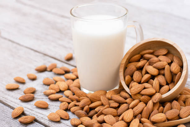 Almond milk wood background. Almonds nuts in wooden bowl and almond milk in glass on wood table background. Almond Milk stock pictures, royalty-free photos & images