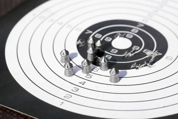 paper shooting target with bullet holes and airgun pellets closeup of paper shooting target with bullet holes and airgun pellets pellet gun stock pictures, royalty-free photos & images