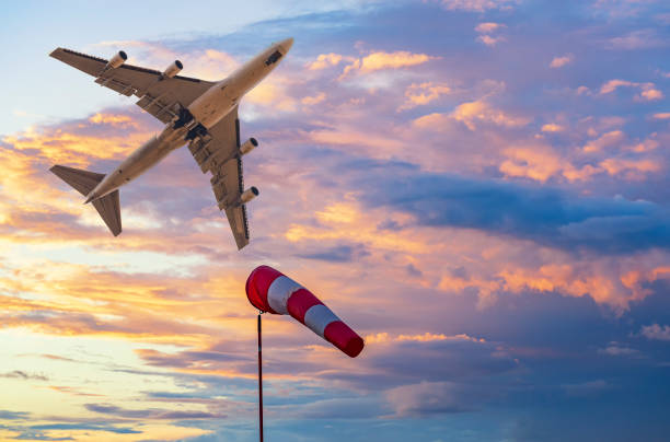 windsock e aereo a getto nel luminoso cielo al tramonto - speed road sign sign forecasting foto e immagini stock