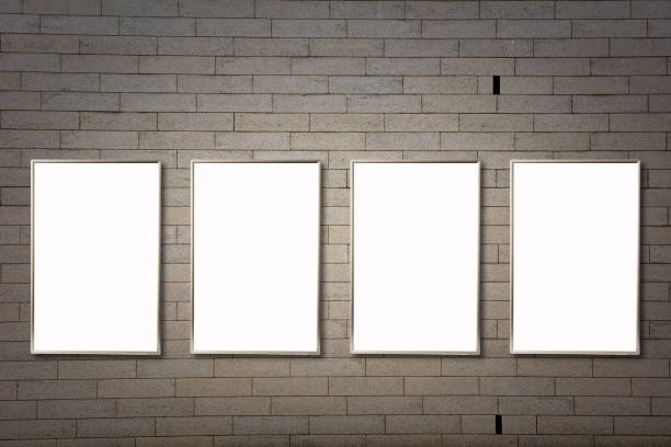 istock Row of four vertical mock-up blank poster frames on a stone wall. 1272361598