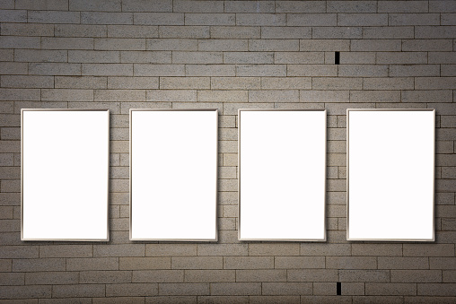 Row of four vertical mock-up blank poster frames on a stone wall with copy space.
