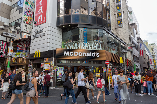 People walk past McDonald's restaurant in Shibuya Center Street, Tokyo, Japan. McDonald's is an American fast food company.