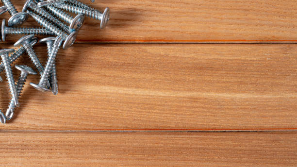 istock Self-cutters on a wood brown background banner with space for text. Construction tools, self-tapping screws for fastening. 1272367789
