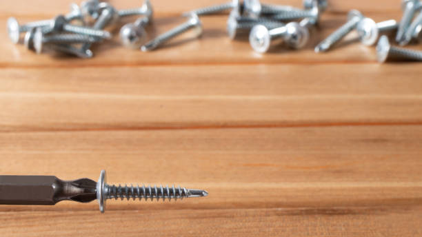 istock Self-cutters and screwdriver on a wooden background with space for text. Screw with thread - fasteners for construction, tools and accessories repair 1272367810