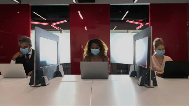 Photo of Group of business people wear face mask and work in social distance with partitions in between as a part of new normal during coronavirus covid 19 in the meeting room at office workplace