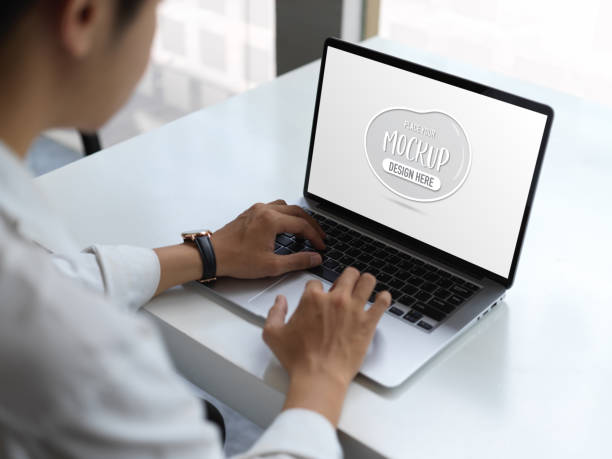 istock Businessman typing on mock up laptop computer in office room 1272370042