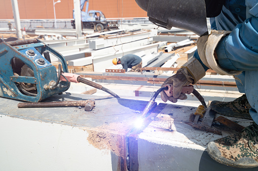 Worker are welding joint connection steel structure roof frame. prepairing for erection steel structure roof truss in the construction site