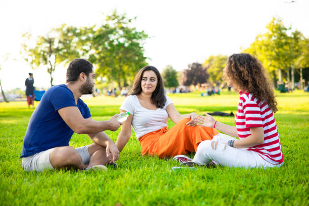 istock Three friends sitting on the grass in the park 1272376147