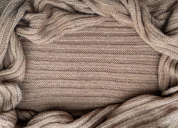 istock Oval frame for text from beige knitted scarf or sweater texture, top view. Texture background of warm crocheted clothing textile. Knitwear fabric. 1272379786