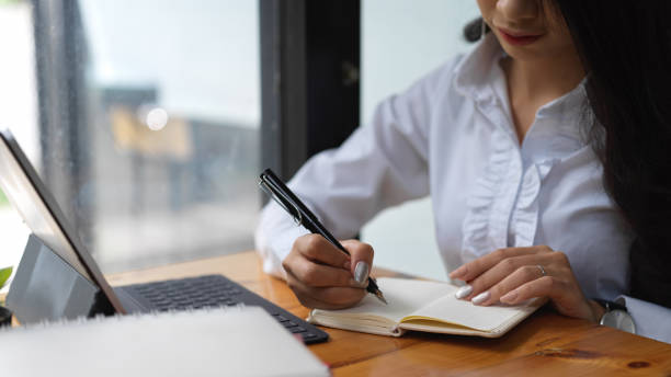 istock Female working with digital tablet and writing an idea in her notebook 1272380046