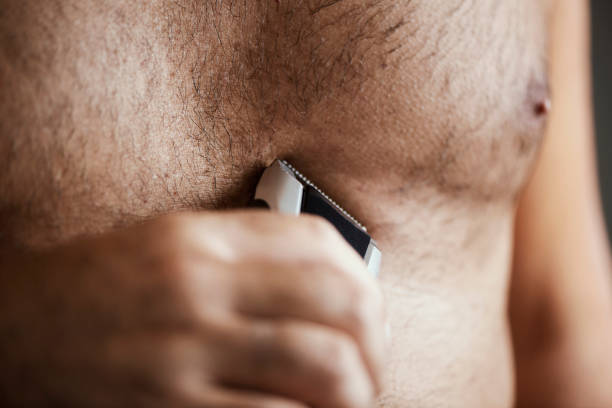 man trimming his chest with an electric trimmer closeup of a young caucasian man in the bathroom trimming the hair of his chest with an electric trimmer body hair stock pictures, royalty-free photos & images