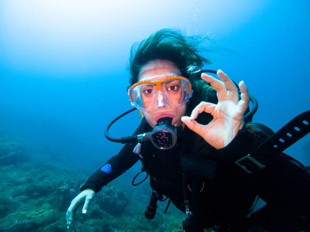 A young female diver making OK sign underwater looking at the camera stock photo