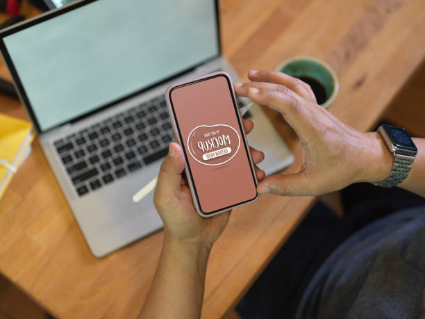 istock Male worker using mock up smartphone above worktable while sitting in office room 1272383041