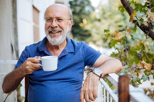 Smiling mature man enjoying in morning coffee on a terrace