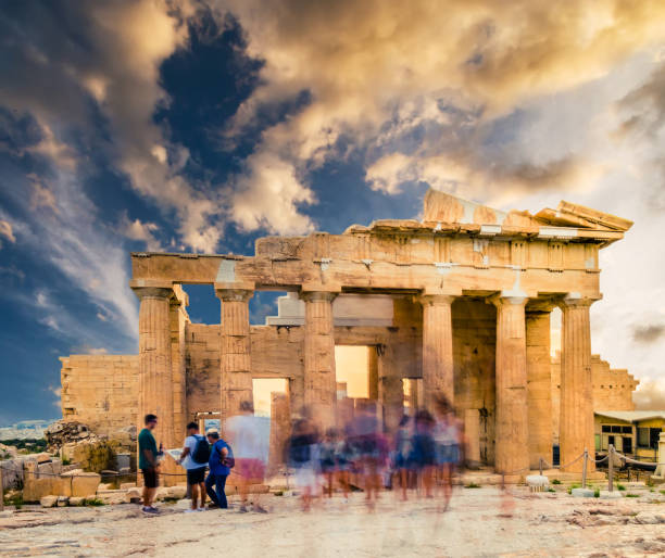 Motion blur image of people strolling around the Parthenon temple on sunny day at sunset, Athens, Greece