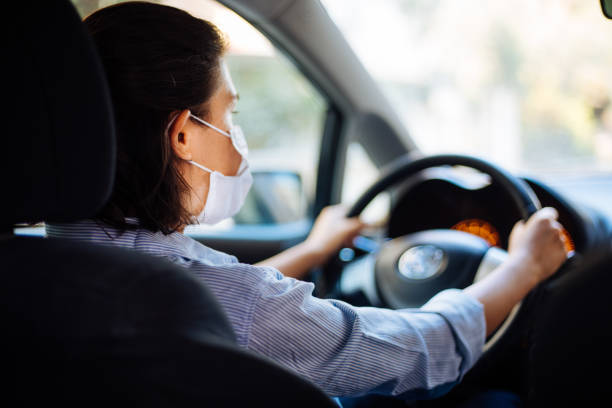 istock Woman in protective mask driving a car on road 1272386290