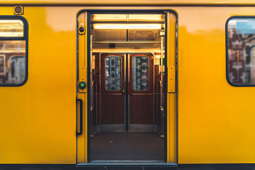 old yellow wagon of traditional berlin metro train with doors open at subway station