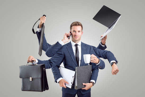 Funny portrait of a businessman with many arms Funny image of a young businessman with 8 arms. He is holding various business objects like laptop, briefcase, tie and files. Isolated on a neutral background. multitasking stock pictures, royalty-free photos & images