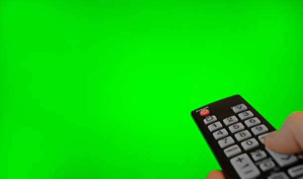 istock Male hand with remote control pointing on TV screen. Green chroma key. 1272403092