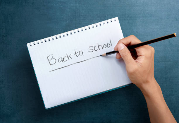 istock Hand with pencil writing in the book 1272403283