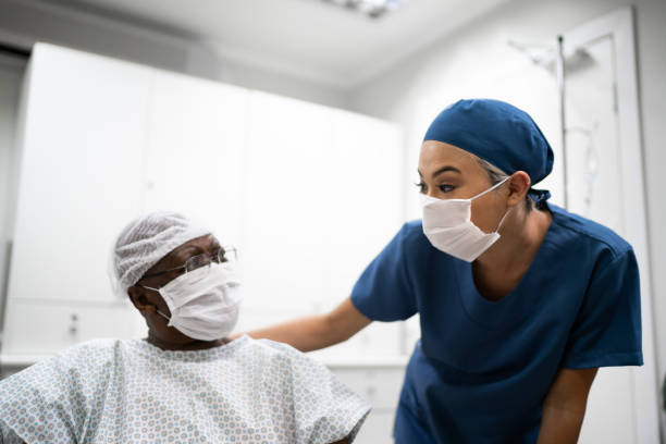 Nurse talking and doing a emotional support to a female senior patient at hospital Nurse talking and doing a emotional support to a female senior patient at hospital surgical mask stock pictures, royalty-free photos & images